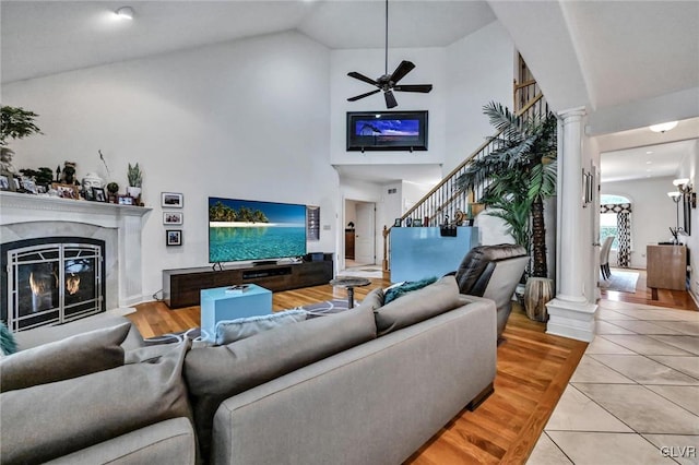 living area with decorative columns, a premium fireplace, stairway, and tile patterned flooring