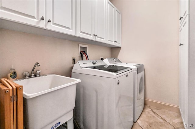 laundry room with washing machine and clothes dryer, cabinet space, light tile patterned flooring, a sink, and baseboards