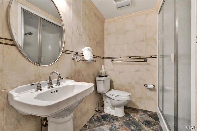 bathroom with crown molding, tile walls, toilet, a stall shower, and a sink