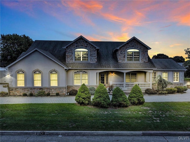 french provincial home featuring driveway, a porch, a front lawn, and stucco siding