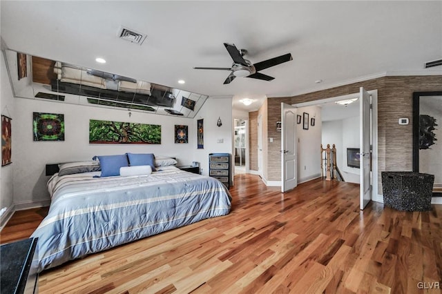 bedroom with a ceiling fan, wood finished floors, visible vents, and baseboards