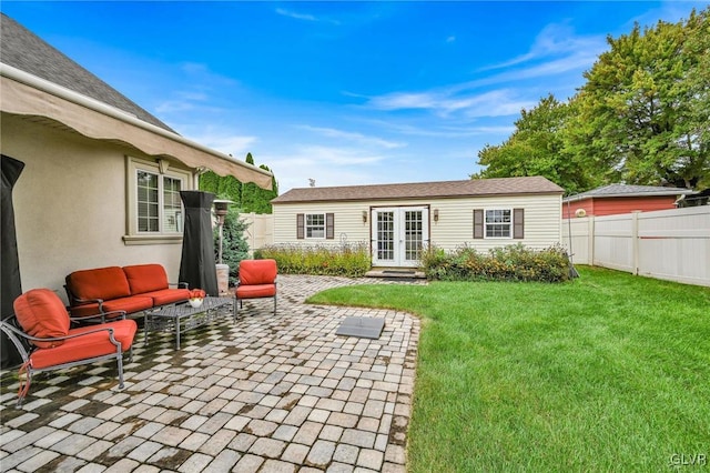 rear view of house with an outbuilding, french doors, a lawn, a patio area, and a fenced backyard