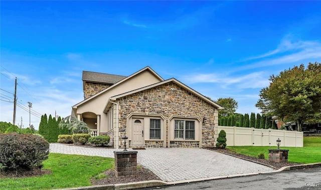 view of front of property with stone siding, fence, stucco siding, and a front yard