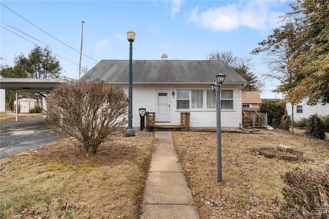 view of front facade featuring a carport, driveway, and a shingled roof