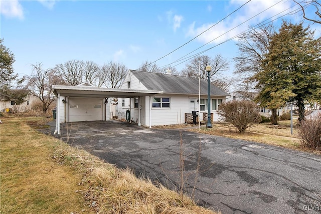 view of front of house with an attached garage, aphalt driveway, an attached carport, and a front yard