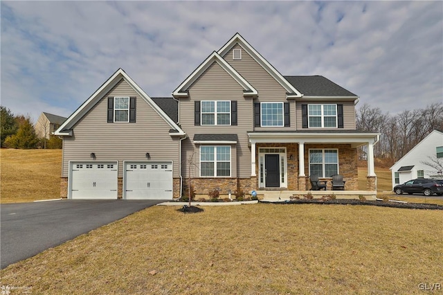 craftsman-style home with a garage, driveway, covered porch, and a front yard