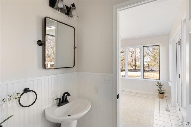 bathroom featuring tile patterned flooring, a wainscoted wall, and a sink