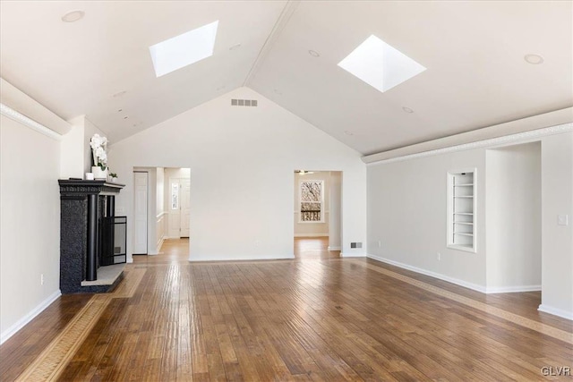 unfurnished living room featuring visible vents, built in shelves, hardwood / wood-style floors, a skylight, and baseboards