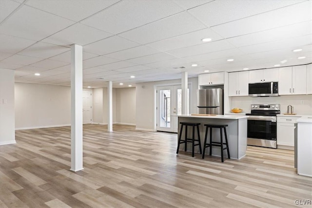 kitchen with a kitchen island, a kitchen bar, stainless steel appliances, light wood-style floors, and white cabinetry