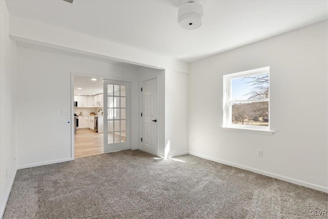 unfurnished room with light colored carpet, french doors, and baseboards