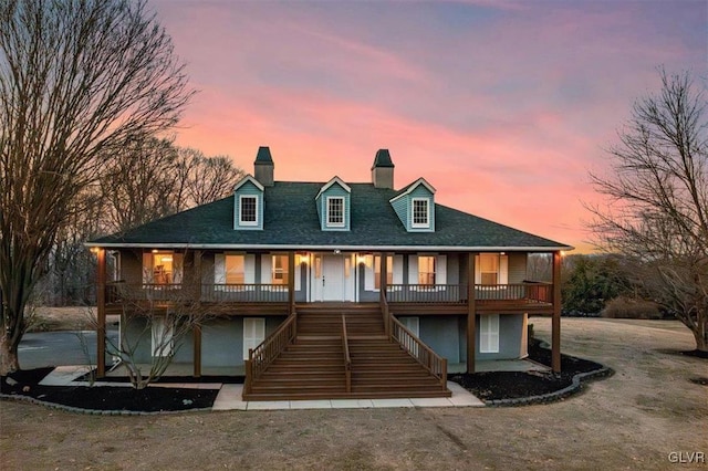 view of front of house featuring a porch, a chimney, and stairs