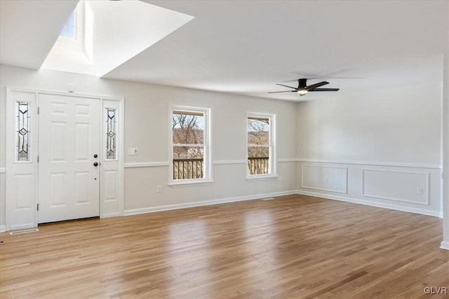 entryway with a decorative wall, light wood-style floors, a wainscoted wall, and ceiling fan