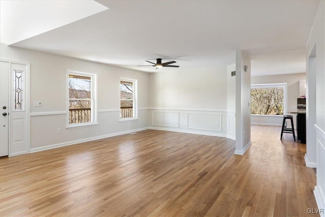 unfurnished living room with light wood-type flooring, plenty of natural light, visible vents, and a ceiling fan