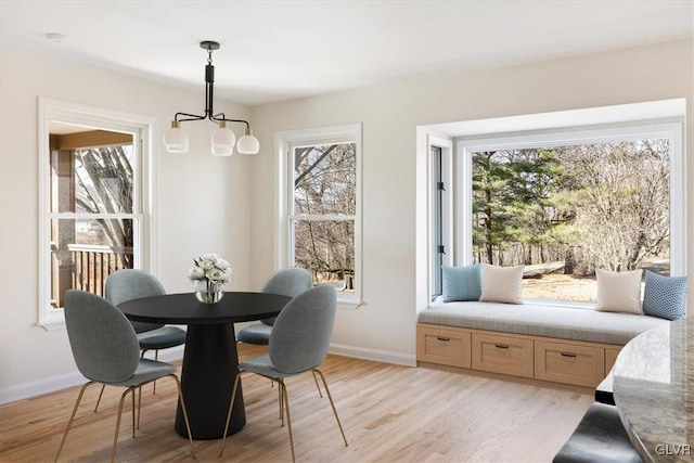 dining room featuring light wood finished floors, a chandelier, and baseboards