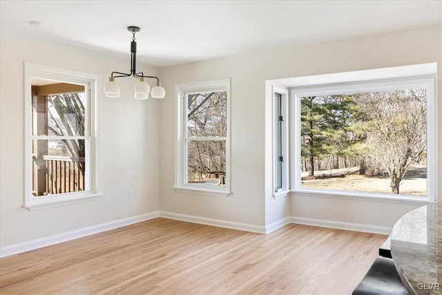 dining space with light wood finished floors, a notable chandelier, and baseboards