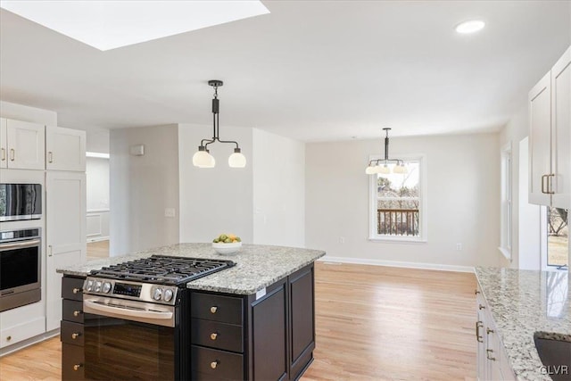 kitchen featuring light stone counters, appliances with stainless steel finishes, white cabinetry, and light wood-type flooring