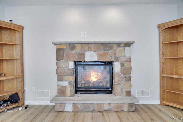 interior details with a fireplace, wood finished floors, visible vents, and baseboards