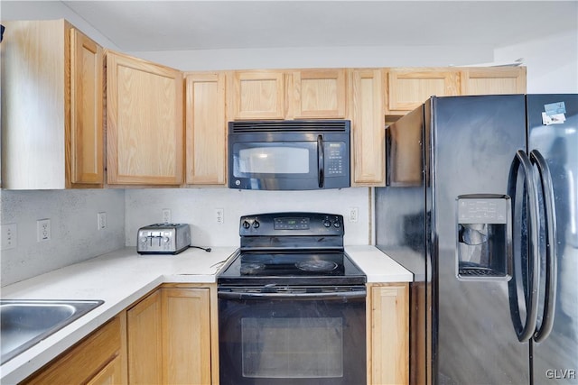 kitchen with black appliances, light countertops, a sink, and light brown cabinetry