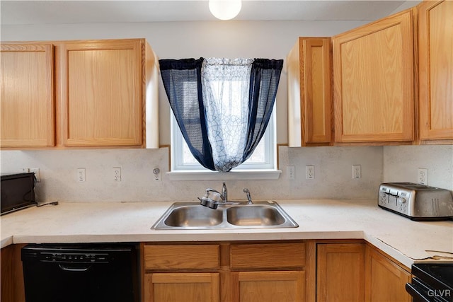 kitchen with black appliances, light brown cabinetry, a sink, and light countertops