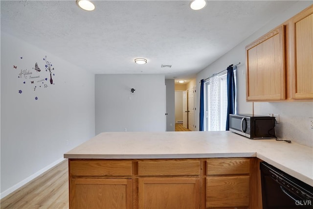 kitchen with light wood finished floors, black dishwasher, stainless steel microwave, a peninsula, and light countertops