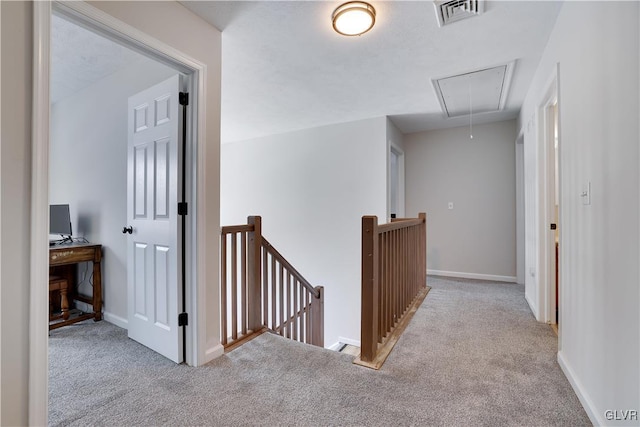 corridor with carpet, visible vents, attic access, an upstairs landing, and baseboards