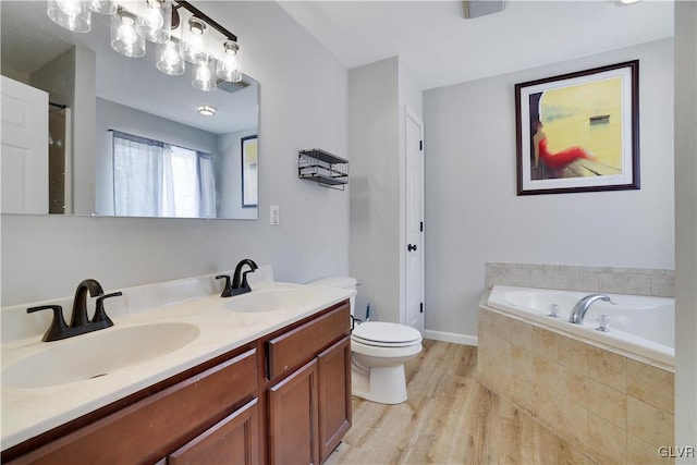 bathroom with double vanity, a garden tub, a sink, and wood finished floors