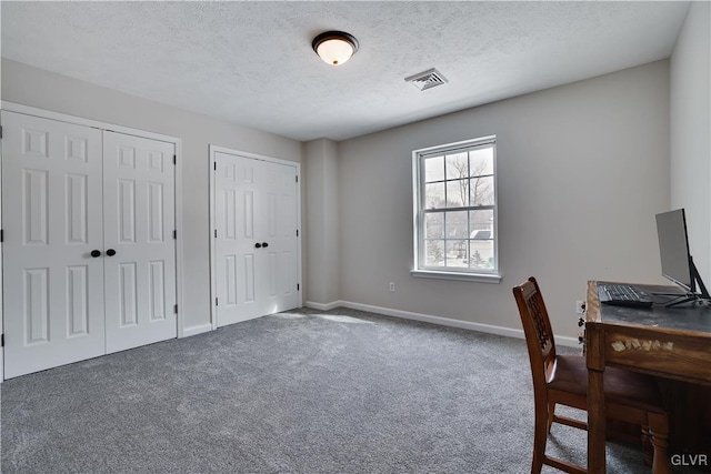 office featuring carpet floors, visible vents, a textured ceiling, and baseboards