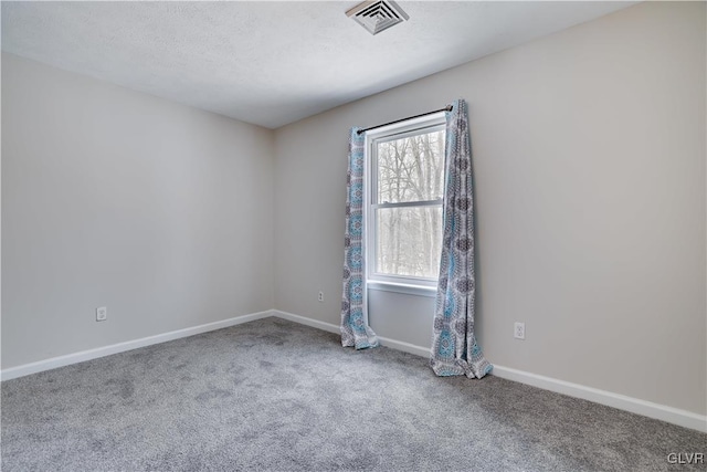 carpeted spare room with visible vents, a textured ceiling, and baseboards