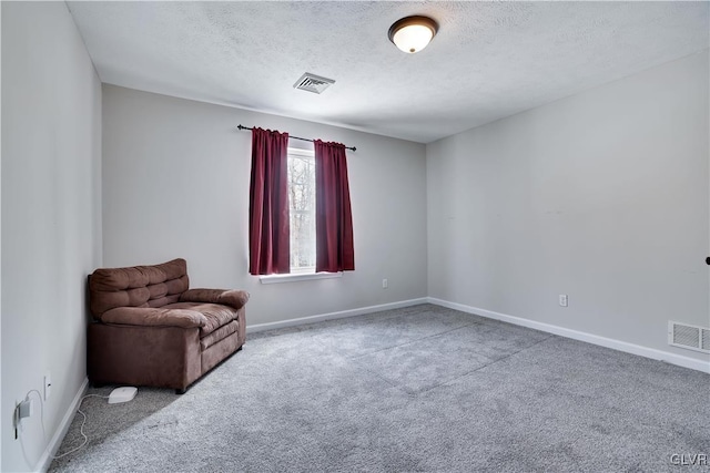 unfurnished room with baseboards, a textured ceiling, visible vents, and carpet flooring