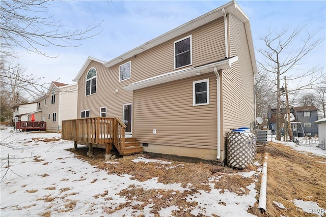 snow covered back of property with a residential view and a wooden deck