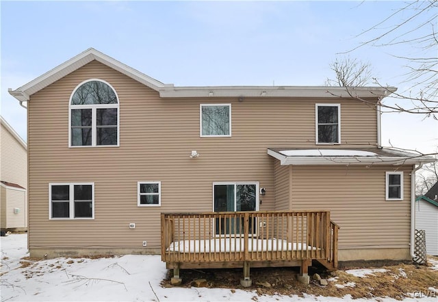 snow covered back of property featuring a deck