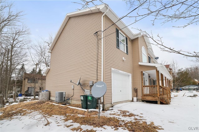 view of snow covered exterior with a garage and central AC unit