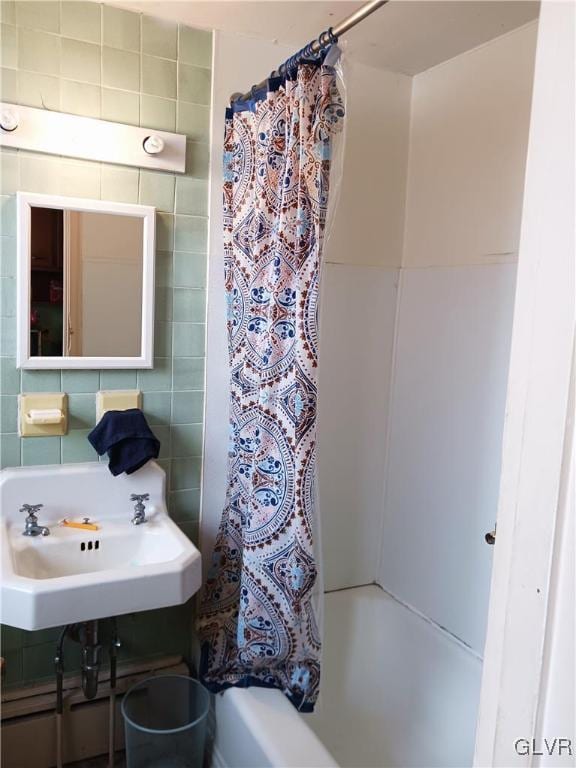 bathroom with a sink, tile walls, and shower / bath combo with shower curtain