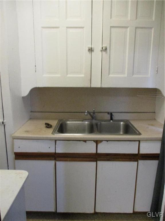 kitchen featuring white cabinets, a sink, and light countertops