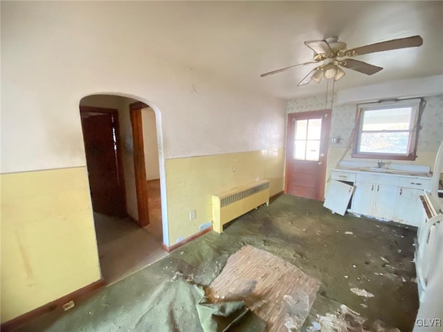 kitchen featuring radiator heating unit, arched walkways, and ceiling fan