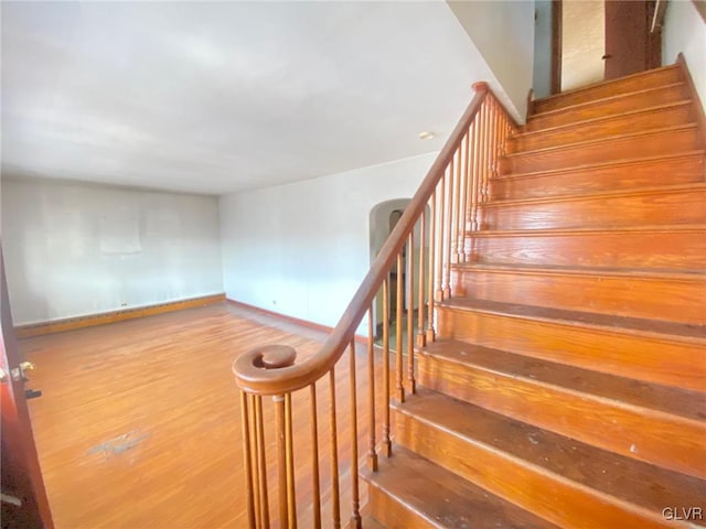 staircase featuring wood finished floors and baseboards