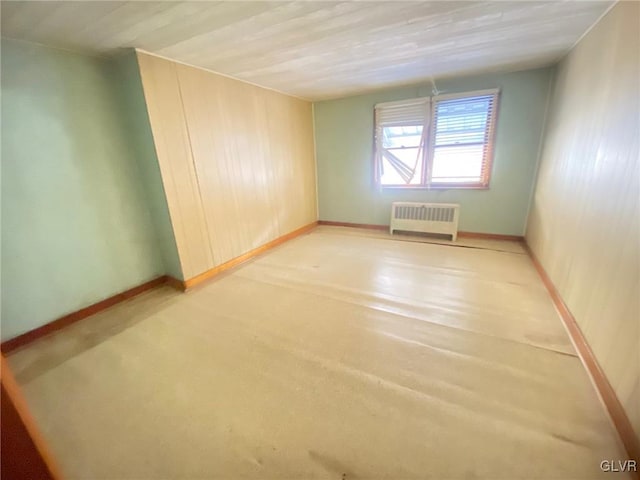 unfurnished room with baseboards and radiator