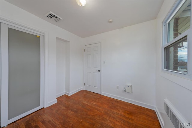 empty room featuring visible vents, baseboards, and wood finished floors