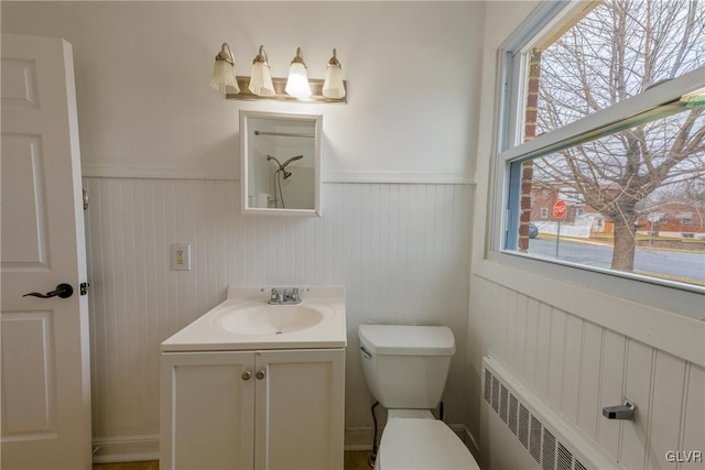 bathroom featuring toilet, a wainscoted wall, radiator heating unit, and vanity