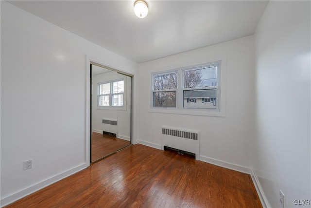 unfurnished room featuring radiator heating unit, baseboards, and wood finished floors