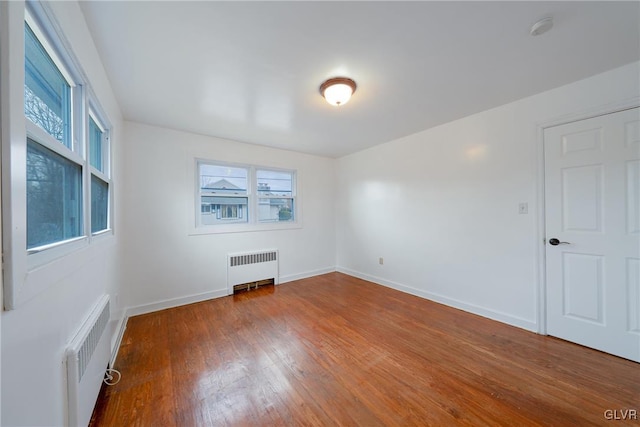 spare room featuring radiator, baseboards, and wood finished floors