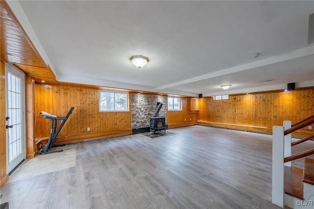 exercise room with wood walls, a wood stove, and light wood-style floors