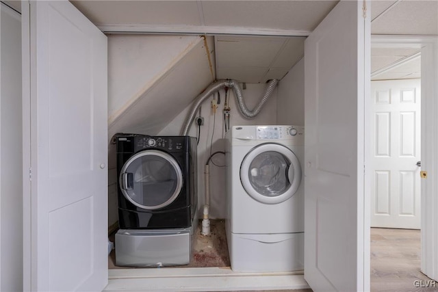 laundry room featuring laundry area, wood finished floors, and washing machine and clothes dryer