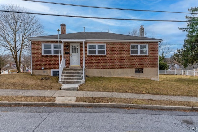 bungalow featuring a front yard, a chimney, fence, and brick siding