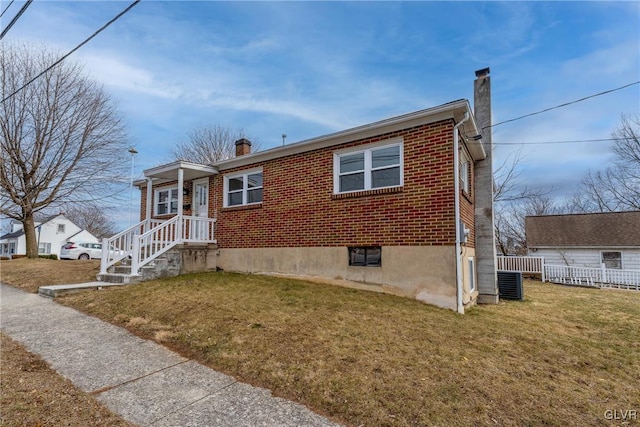 view of front of house featuring brick siding, a chimney, a front lawn, and fence