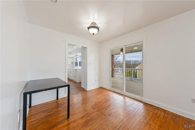 unfurnished dining area featuring wood-type flooring and baseboards