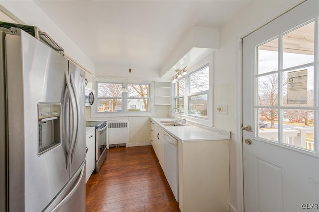 kitchen with radiator heating unit, dark wood-type flooring, stainless steel appliances, light countertops, and a sink