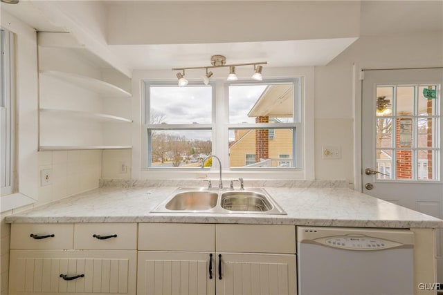 kitchen with a healthy amount of sunlight, white dishwasher, a sink, and white cabinetry