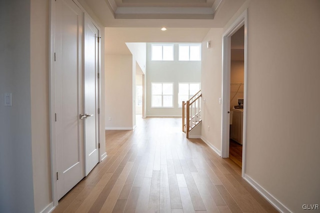 corridor featuring stairway, light wood-style flooring, and baseboards