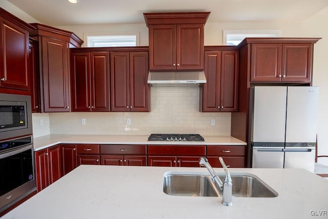 kitchen featuring dark brown cabinets, appliances with stainless steel finishes, a sink, and under cabinet range hood